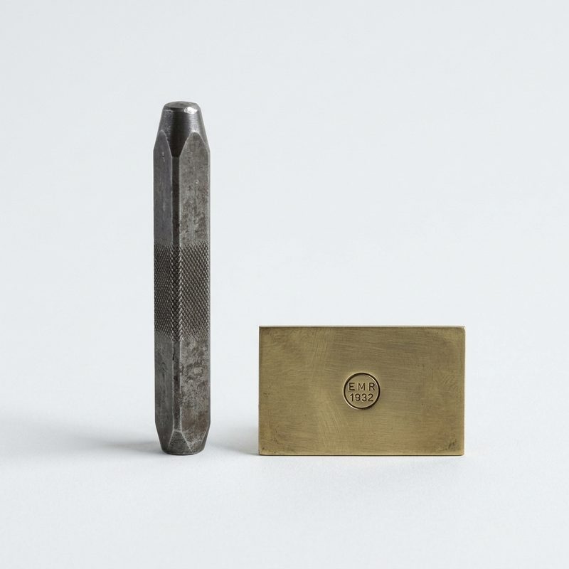Steel hand punch beside its stamped maker’s mark in a brass plate